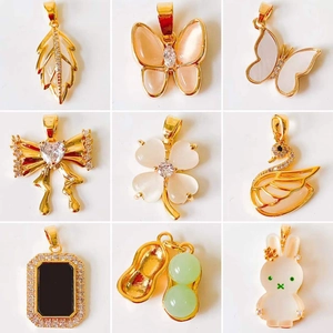Macro shot of various 18k gold plated charms including clover, butterfly, and swan designs