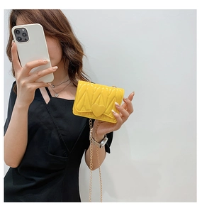 Detail of yellow quilted silicone bag with heart decoration and gold chain strap