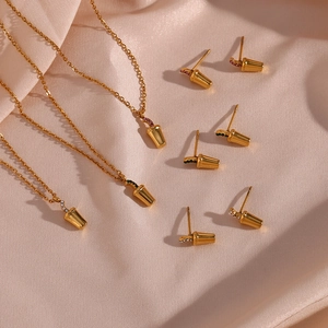 Macro detail of gold-plated drink cup pendants with colorful zircon inlay on pink silk