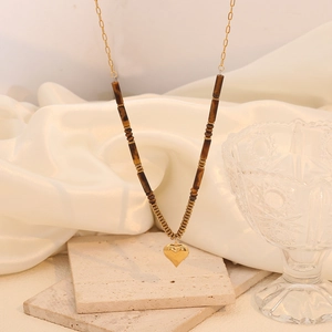 Detail of gold heart pendant and brown tiger eye beads on double-layered stainless steel chain