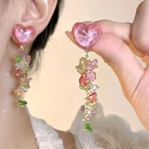 Detail of pink heart-shaped earrings with colorful stone tassels on a golden chain