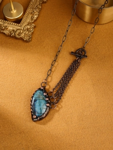 Detailed macro view of an irregular blue labradorite pendant on bronze metal chain