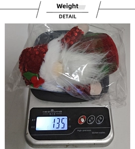 Mesure du poids d'un gnome de Noël à paillettes rouges avec barbe blanche, 135g sur balance