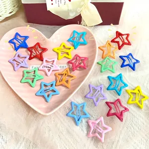 Colorful star-shaped metal hair clips in various bright colors on a pink tray