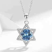Detailed view of silver hexagonal star pendant with a blue gemstone and white pavé crystals