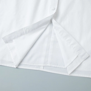 Gros plan d'une robe blanche montrant les coutures et le détail du bouton mat