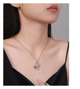 Close-up of heart necklace featuring a girl and dog pendant worn by a model