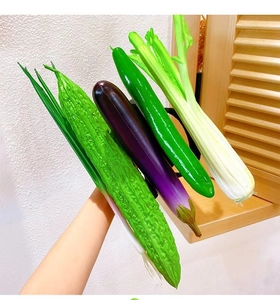 Hand holding realistic plush vegetable headbands featuring cucumber, eggplant and celery