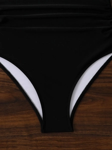 Dettaglio macro del costume intero nero con texture arricciata in vita e fodera bianca