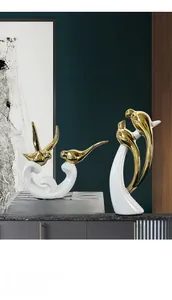 Detail of luxury ceramic bird figurines in white and gold on a modern dark cabinet