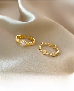 Detail of two gold rings with white pearls on elegant beige silk background