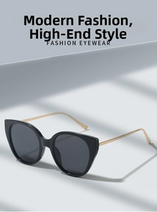 Detail of cat-eye sunglasses featuring black frames and gold metal temples on a grey background
