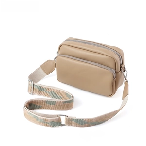 Dettaglio borsa a tracolla beige con doppia cerniera e tracolla in tessuto jacquard