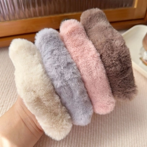 Close-up of plush hair clips in beige, grey, pink and brown showing soft fluffy texture