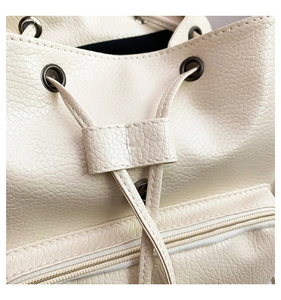 Close-up of white lychee texture PU leather backpack with drawstring and metal eyelets