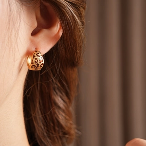 Close-up of vintage leopard print hoop earrings on model with golden finish