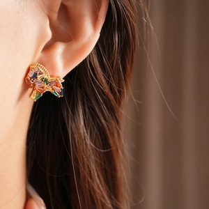 Close-up of golden cluster earrings with colorful rectangular-cut zircon stones on model