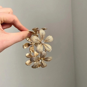 Golden flower bracelet with grid texture and rhinestone center on minimalist elastic band