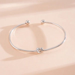Verfijnd detail van een zilveren minimalistische open armband met knoopontwerp