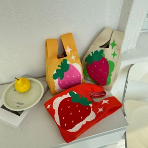 Detailed close-up of three knitted strawberry tote bags in yellow, cream, and red colors