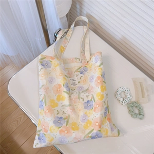 Detail of floral canvas tote bag with yellow and purple flowers and white woven label