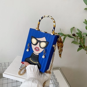 Detail of blue box clutch bag featuring cartoon graffiti and elegant silk scarf handle