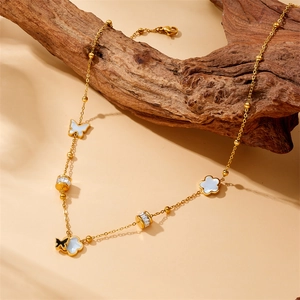 Gold-plated stainless steel necklace with flower and butterfly charms on driftwood