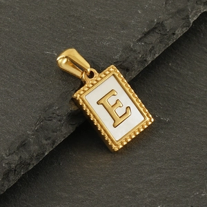 Makroaufnahme Goldanhänger mit Buchstabe E auf dunkelgrauem Schieferstein
