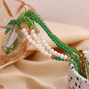 Detail of beaded necklace with green faceted crystals, freshwater pearls and gold beads