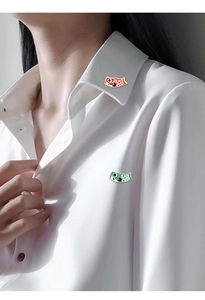 Detail view of colorful koi fish enamel pins on a white shirt collar for daily styling