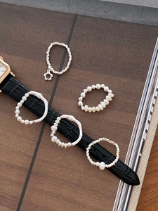 S925 silver rings with pearls and flower pendants on black leather strap background