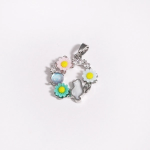 Detailed shot of a silver wreath pendant with colorful daisies, zircons and a white cat motif