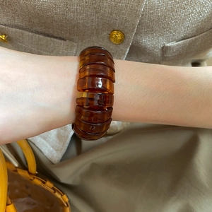 Detailed view of an amber resin chunky bracelet on a wrist with a soft neutral background
