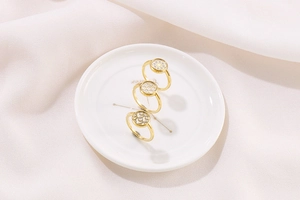 Three gold rings with honeycomb lattice pattern on a white ceramic plate with silk cloth