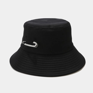 Dettaglio di un cappello da pescatore nero con spilla di strass su tessuto a trama piana
