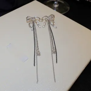 Détail de boucles d'oreilles nœud de luxe avec perles blanches et strass brillants