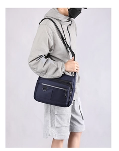 Side view of navy blue nylon messenger bag showing multi-pocket design and adjustable strap