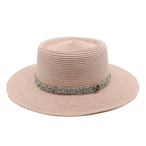 Close-up of pink straw boater hat with sequin band and gold M logo detail