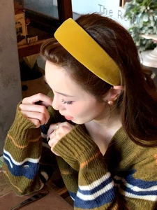 Detail of a thick mustard yellow velvet headband providing a high top hair volume effect