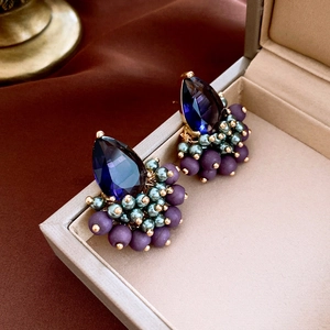Macro detail of vintage teardrop earrings with blue gemstones and purple bead accents