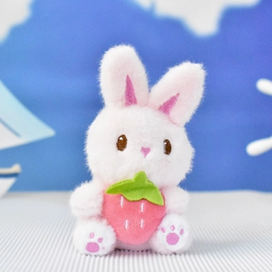 Close-up of adorable pink plush bunny charm holding a strawberry for bags and backpacks