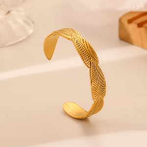 Detailed view of the gold leaf texture and open cuff design of the stainless steel bracelet