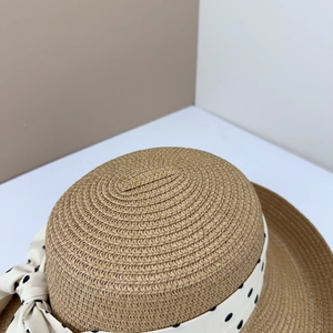 Detail of handwoven khaki straw hat featuring a chic polka dot ribbon and silk bow