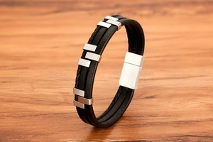 Close-up of men's black leather bracelet with silver accents on a wooden background