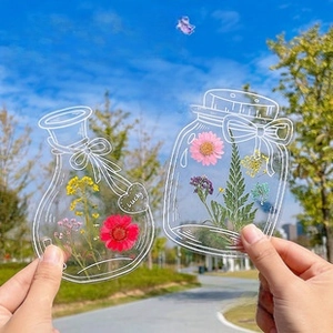 Transparentes Lesezeichen in Einmachglasform mit bunten gepressten Trockenblumen im Freien