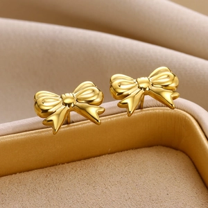 Macro shot of gold-plated bow earrings on a beige velvet jewelry display
