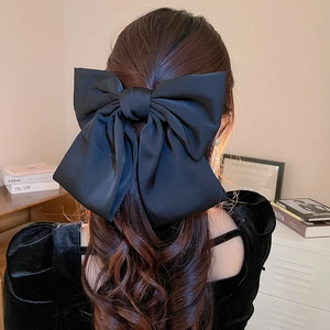 Détail de la pince à cheveux élégante avec nœud en satin noir et design multicouche lisse