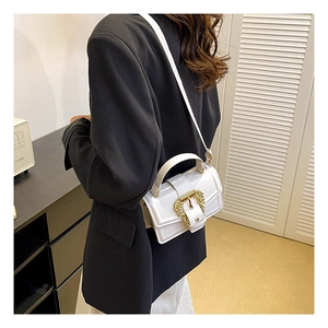 Close-up of white leather shoulder bag with vintage gold embossed buckle on black blazer