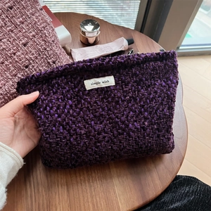 Detail of purple tweed makeup bag with woven texture and a simple wish label