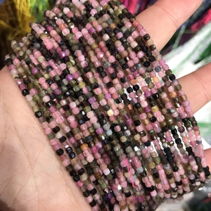 Close-up of hand holding 2-3mm faceted natural crystal stone beads for DIY jewelry